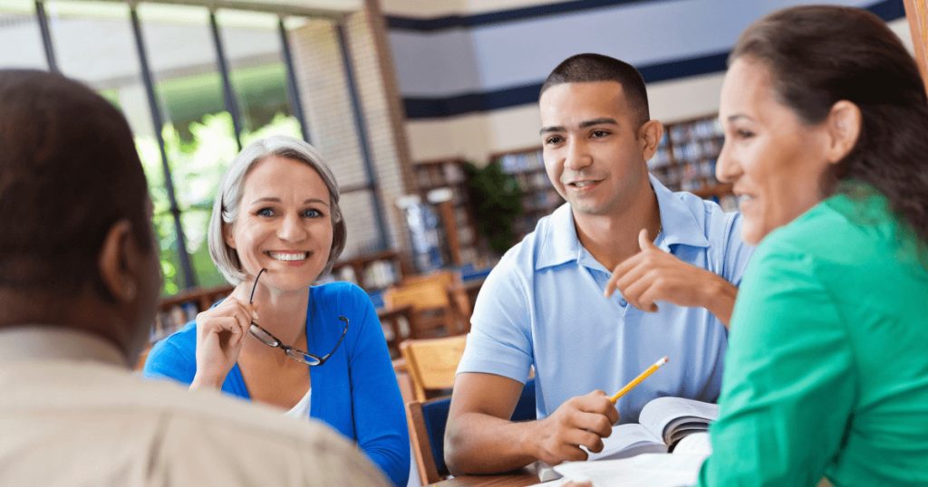 Mehrere lächelnde Menschen im Austausch. Symbolisch für einen Workshop zum Thema Online Marketing.