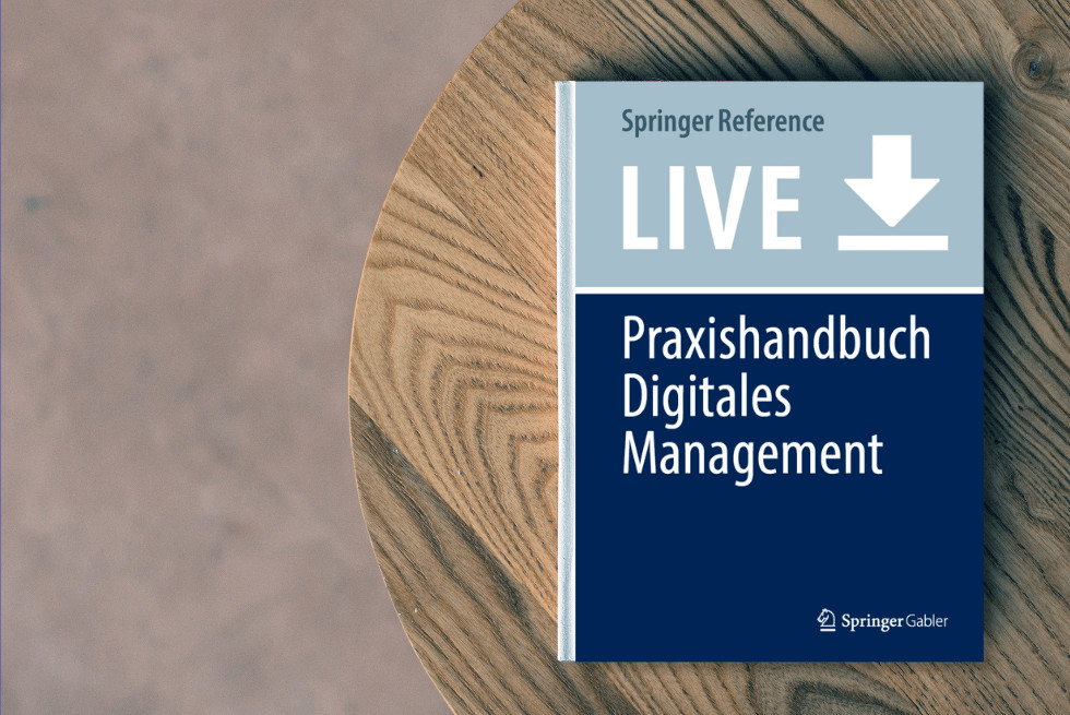 Brauner, runder Tisch, auf dem das Buch "Praxishandbuch Digitales Management" liegt.